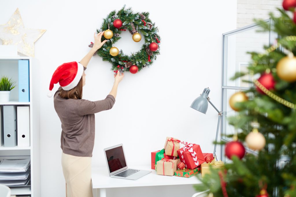 Frau mit Weihnachtsmütze dekoriert Büro