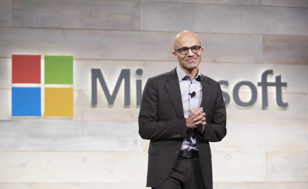 Satya Nadella steht vor dem Microsoft Logo
