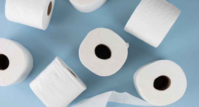 blauer Hintergrund. davor sieben rollen Toilettenpapier in weiß die durcheinander liegen