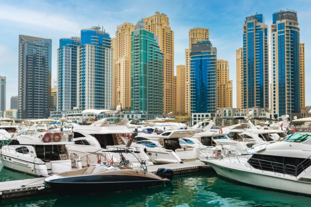 Hafen mit kleinen Yachten vor Wolkenkratzern in blau, grün, gold und grau in Dubai