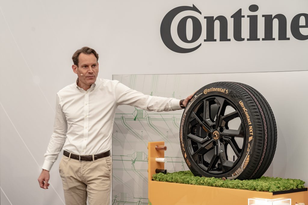 Nikolai Setzer als CEO von Continental steht mit einem weißen Hemd und einem Mikrofon neben einem Reifen von Continental auf den er eine Hand legt