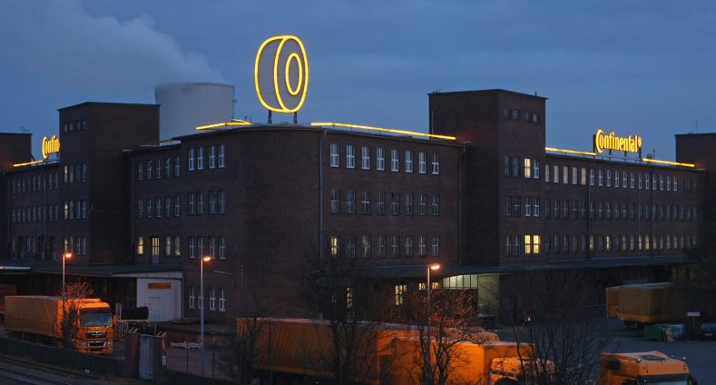Firmengebäude von Continental bei Nacht mit einem Reifen am Dach des Unternehmens der gelb beleuchtet ist und der Schriftzug von Continental