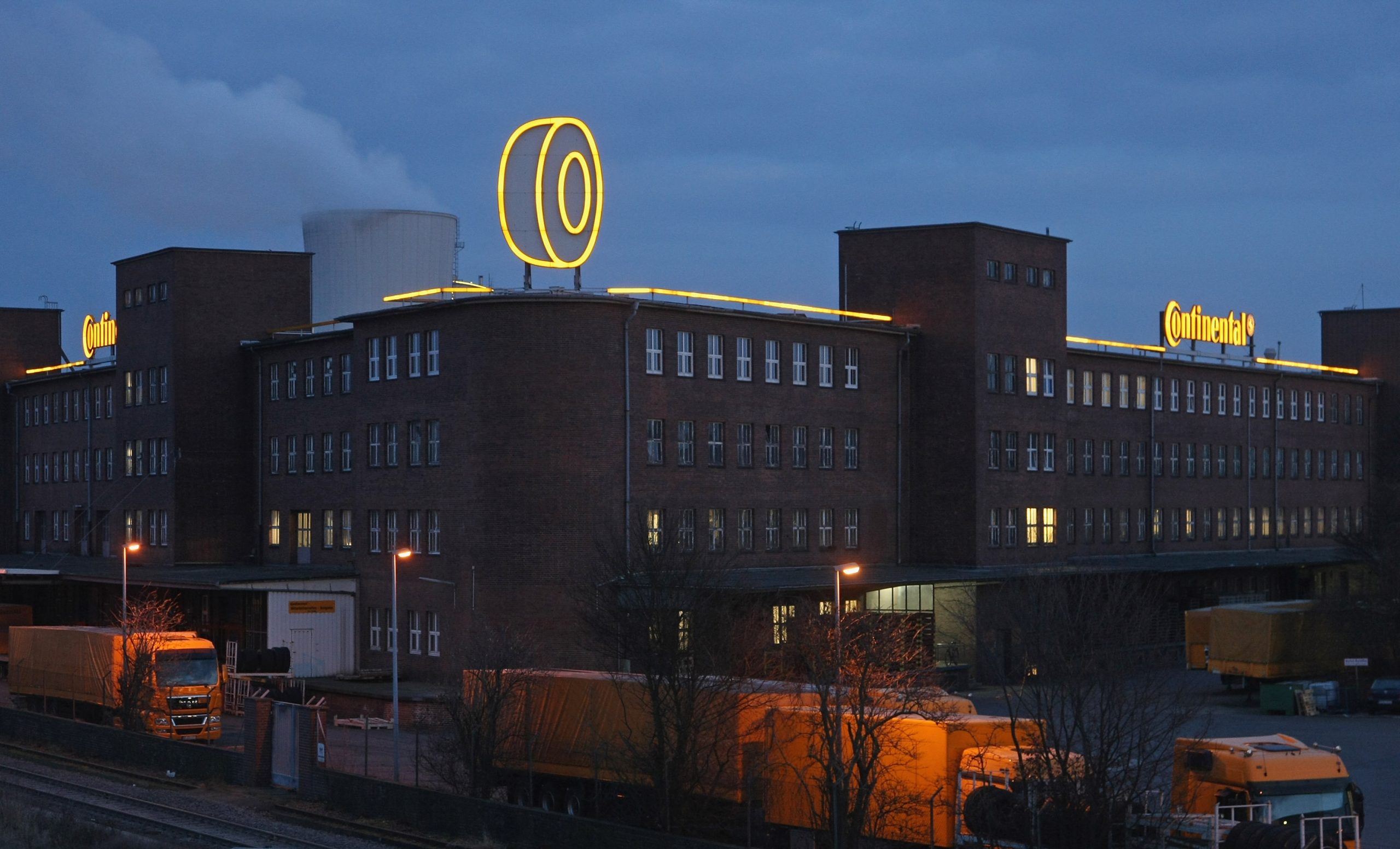 Firmengebäude von Continental bei Nacht mit einem Reifen am Dach des Unternehmens der gelb beleuchtet ist und der Schriftzug von Continental