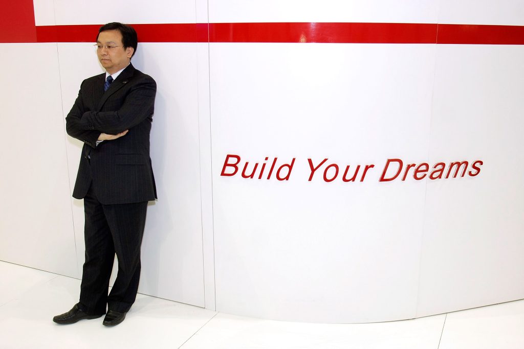 BYD-Gründer Wang Chanfu steht neben BYD-Slogan 