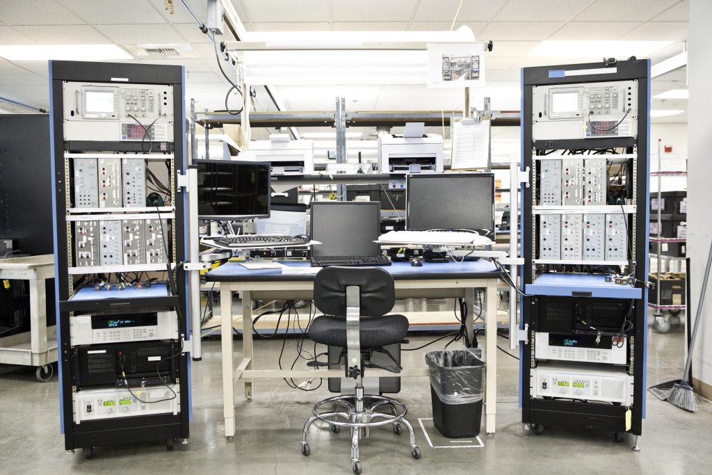 Blick in ein Labor mit einem Tisch, vielen Computern und einem Sessel sowie sehr viele Analyseinstrumente herum