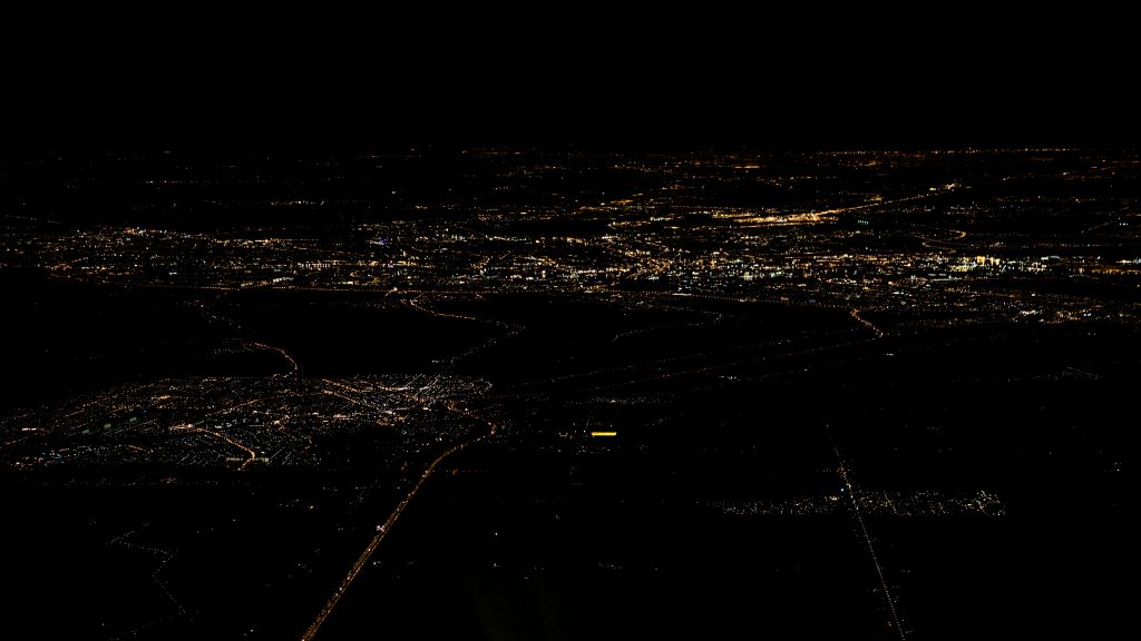 Blick aus einem Flugzeug in der Nacht über eine Stadt