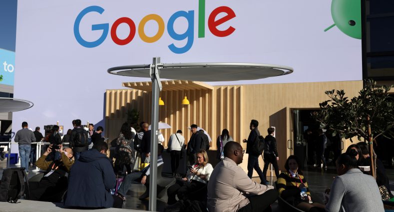 Logo von Google auf einer Hauswand. Davor einige junge Menschen