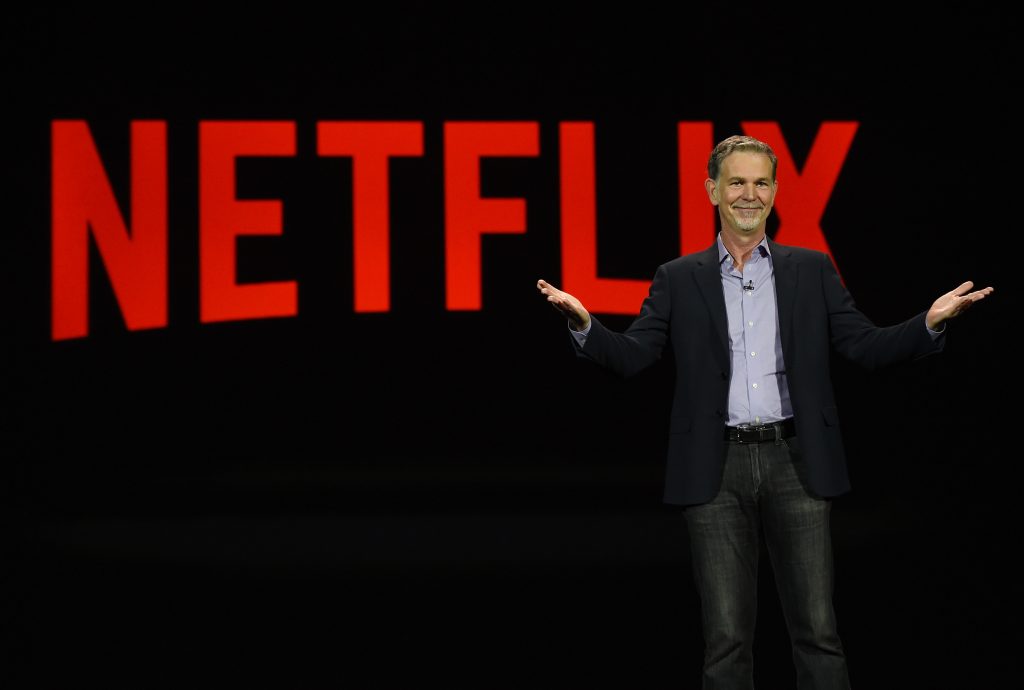 Logo von Netflix und Reed Hastings auf einer Bühne