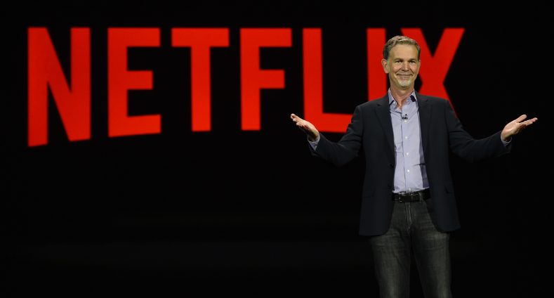 Logo von Netflix und Reed Hastings auf einer Bühne